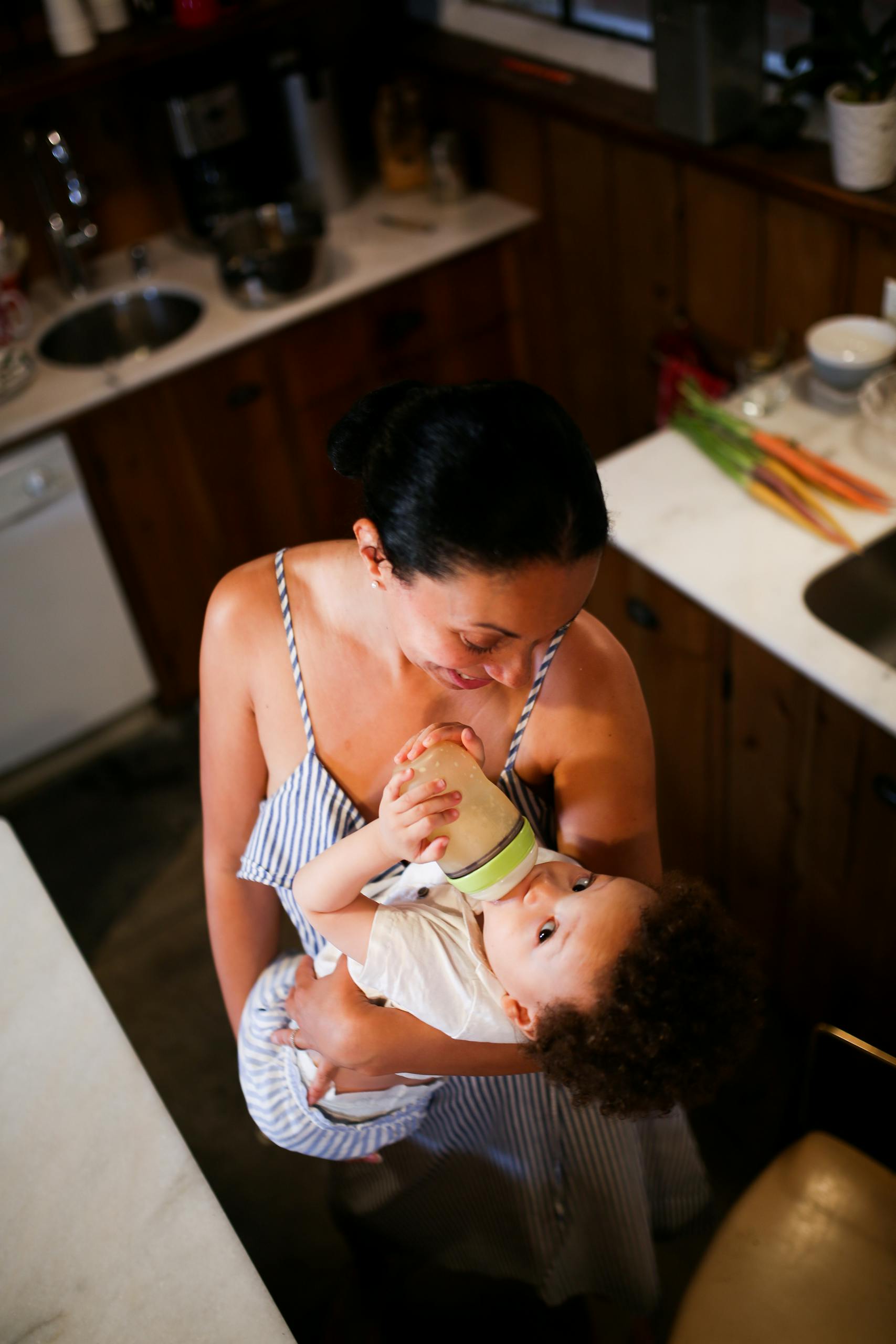 A Mother Carrying a Baby Drinking on a Bottle