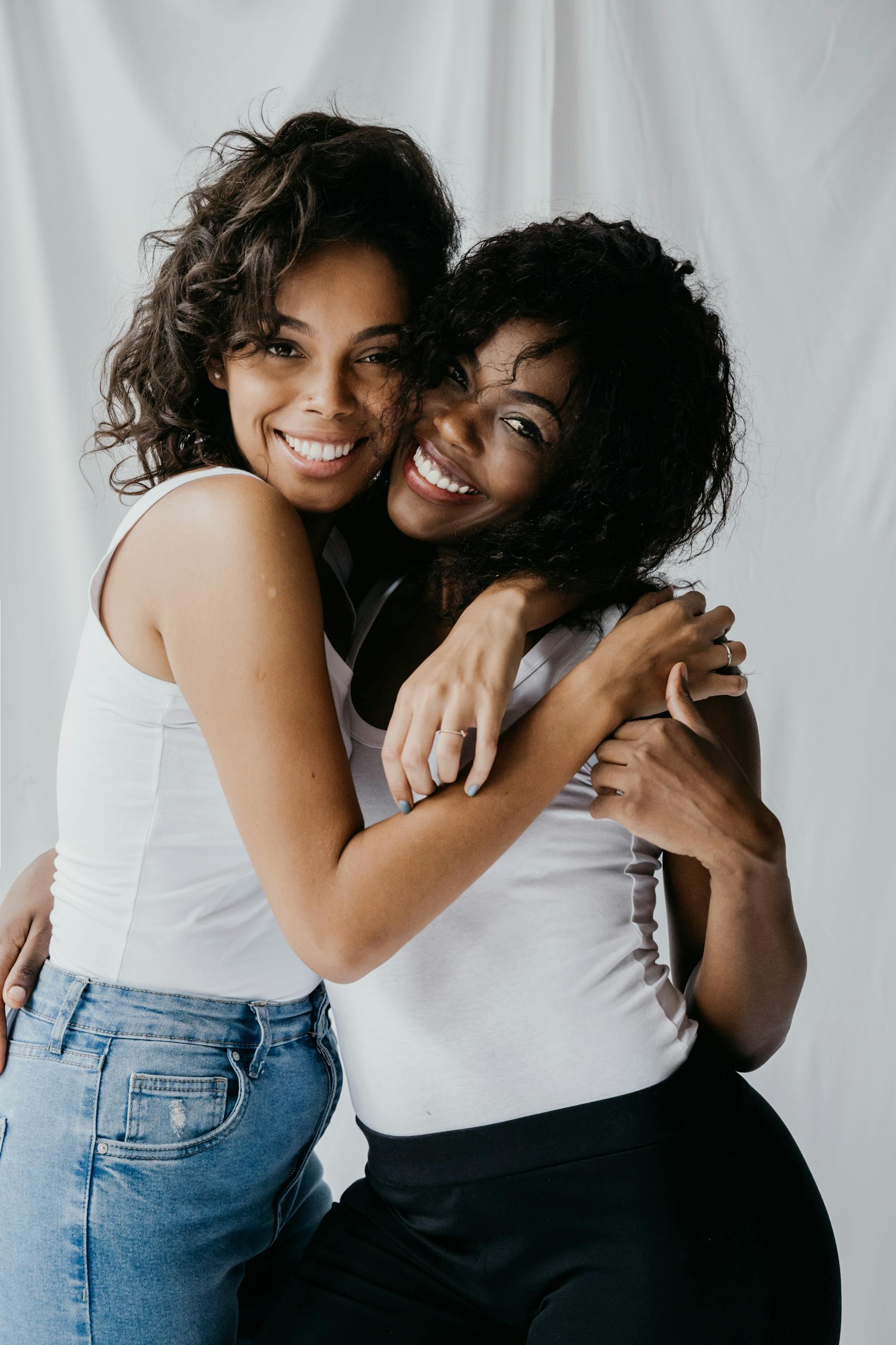 Women in White Tank Top Hugging Each Other